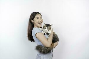 Portrait of young Asian woman holding cute angora cat with yellow eyes. Female hugging her cute long hair kitty isolated by white background. Adorable domestic pet concept. photo