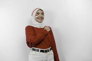 Beautiful Asian woman wearing red top and white hijab giving salute celebrate Indonesian independence day on August 17 isolated over white background photo