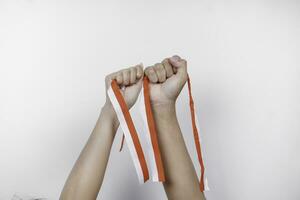 hands put together holding Indonesian red and white ribbon. Indonesia's independence day concept photo