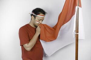 Indonesian man give salute with proud gesture while holding Indonesia's flag. Indonesia's independence day concept. photo