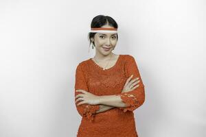 A confident Indonesian woman folding her arms and wearing red kebaya and Indonesia's flag headband to celebrate Indonesia Independence Day. Isolated by white background. photo