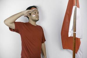 Indonesian man give salute with proud gesture while holding Indonesia's flag. Indonesia's independence day concept. photo