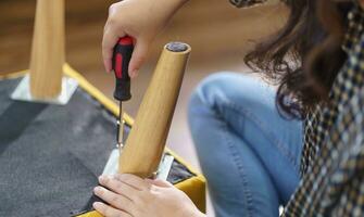 Asian Woman self repairs furniture renovation using equipment to diy repairing furniture sitting on the floor at home photo