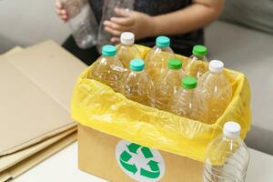 hogar reciclar eco verde cero concepto mujer lanzamiento vacío el plastico botella en reciclaje compartimiento con amarillo basura pantalones a hogar. foto