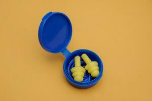 yellow silicone ear plugs with ear plug storage tubes isolated on yellow background photo