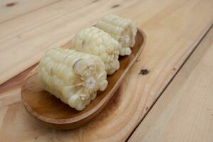 a simple dish of boiled glutinous corn with a dominant white color on a wooden tray with chili sauce photo