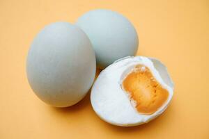 Telur Asin, Homemade Salted Egg, Made from Duck Egg and Coarse Salt with Traditional Method isolated on yellow background photo