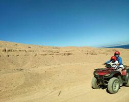 mamá con un hijo yendo mediante el Desierto en un equipo bicicleta, sinaí montañas, colinas foto