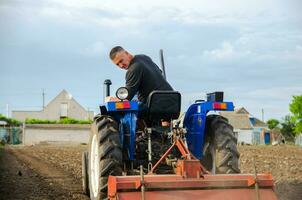 Kherson oblast, Ukraine - May 29, 2021 A farmer on a tractor cleans the field after harvest. Preparation of land for future planting new crop. Milling soil, loosening ground before cutting rows photo