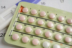 Pregnancy test with birth control pills and condom for female on calendar, ovulation day. photo