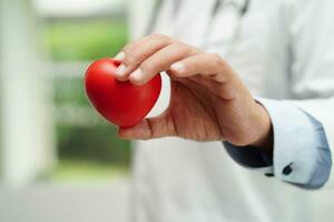 Asian woman doctor holding red heart for health in hospital. photo