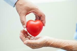 Asian woman doctor holding red heart for health in hospital. photo