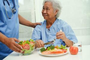 Asian Nutritionist holding healthy food for patient in hospital, nutrition and vitamin. photo