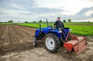 Kherson oblast, Ukraine - May 29, 2021 A farmer on a tractor clears the field. Milling soil, loosening ground before cutting rows. Preparation of land for future planting new crop. photo