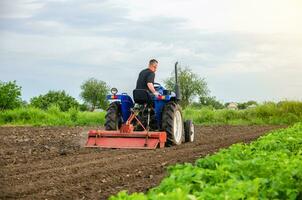 A farmer is cultivating a farm field. Milling soil, crushing before cutting rows. Loosening surface, land cultivation. Plowing field. Removing roots and plant tops. Farming, agriculture. photo