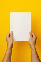 A human hand holding a blank sheet of white paper or card isolated on yellow background. ai generated photo