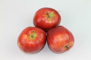 Juicy red apples, standing alone on a pristine white canvas. Nature's temptation in a vibrant display. photo