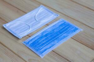 Two pieces of blue Sanitary mask on wooden background, medical mask, medical protective mask, blue surgical mask, Face mask for corona virus protection covid-19 . photo