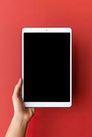 Hand holding tablet with mockup blank screen isolated on red background. ai generated photo