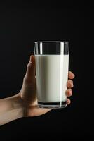 Hand holding a glass of fresh milk isolated on black background. ai generated photo