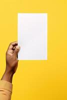A human hand holding a blank sheet of white paper or card isolated on yellow background. ai generated photo