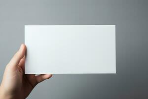 A human hand holding a blank sheet of white paper or card isolated on grey background. ai generated photo