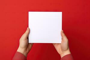 A human hand holding a blank sheet of white paper or card isolated on red background. ai generated photo