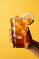 A hand holding takeaway plastic cup of delicious iced lemon tea isolated on yellow background. ai generated photo