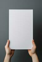 A human hand holding a blank sheet of white paper or card isolated on grey background. ai generated photo