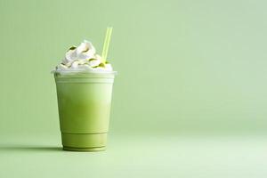 Green tea frappucino with whipped cream in a takeaway cup isolated on green background with copy space. photo
