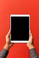 Hand holding tablet with mockup blank screen isolated on red background. ai generated photo