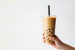 A hand holding takeaway plastic cup of delicious iced bubble milk tea and black pearls isolated on white background with copy space. ai generated photo