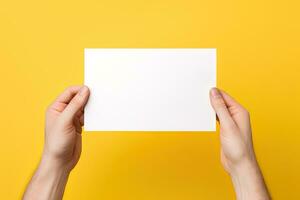 A human hand holding a blank sheet of white paper or card isolated on yellow background. ai generated photo