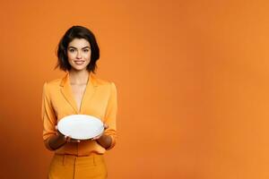 Young beautiful stylish woman holding an empty plate or dish isolated on orange background with copy space. ai generated photo