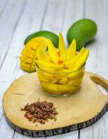 a bowl of sliced mango on a wooden cutting board photo