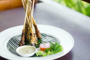 Sate lilit, Balinese food, a plate with skewers and a bowl of sauce photo