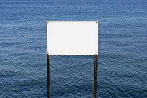 blank white board in front of the blue sea photo