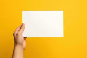 A human hand holding a blank sheet of white paper or card isolated on yellow background. ai generated photo