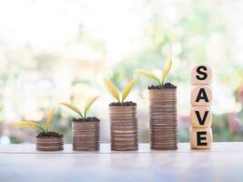 plantas creciente arriba en apilar de monedas y de madera bloques con el palabra ahorrar. el concepto de salvar dinero para preparar en el futuro. foto