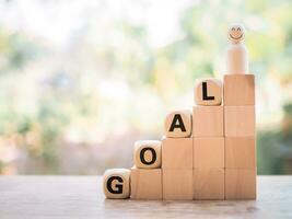 Wooden human figure and wooden blocks with the word GOAL, The concept of business strategy for success and winner concept photo