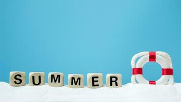 summer word made of wooden letters with life preserver on blue background photo