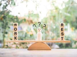 Wooden human figure with question marks. The choice between work and rest. photo