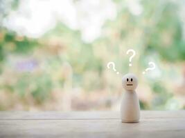 Wooden human figure with question marks. The concept of question or answer time. photo