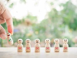 Close up hand holding happy face wooden figure. Customer service rating experience, feedback emotion and satisfaction survey. photo