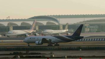 Bangkok, Thailand Januar 21, 2023 - - boeing 777 von thailändisch Atemwege Landung beim suvarnabhumi Flughafen. Verkehrsflugzeug berühren das Runway und Bremsung im Sonnenlicht. Seite Aussicht von ein Flugzeug im Hintergrundbeleuchtung video