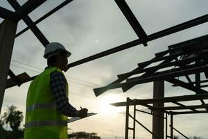 el inspector o ingeniero está inspeccionando la construcción y el aseguramiento de la calidad de la nueva casa usando una lista de verificación. ingenieros o arquitectos o contratistas trabajan para construir la casa antes de entregársela al propietario foto