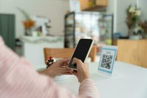 Woman use smartphone to scan QR code for order menu in cafe restaurant with a digital delivery. Choose menu and order accumulate discount. E wallet, technology, pay online, credit card, bank app. photo