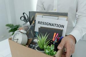 Stressful businessmen will resign from the company. He is lifting a brown paper box that holds personal items. resignation, job placement and vacancies concept. photo