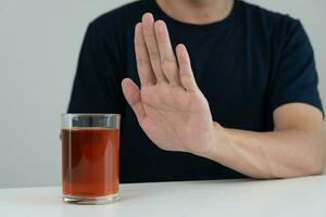 hombre se niega decir No y evitar a bebida un alcohol whisky , parada mano firmar masculino, alcoholismo tratamiento, alcohol adiccion, dejar bebida alcohólica, detener Bebiendo alcohol. negar vaso espíritu, insalubre, rechazar foto