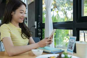 Woman use smartphone to scan QR code to pay in cafe restaurant with a digital payment without cash. Choose menu and order accumulate discount. E wallet, technology, pay online, credit card, bank app. photo